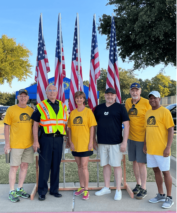 Chris Graham with Lake Cities Chamber volunteers and police at the Lake Cities Bike Rally, Rotary flags flying behind them