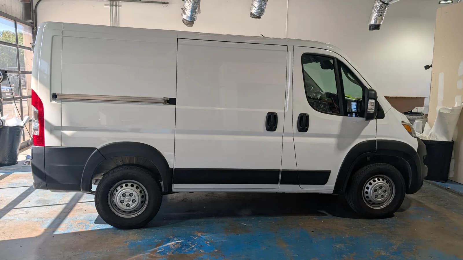 The Discreet Plumbing Ram ProMaster before the wrap, plain factory white in the WrapMasters install bay