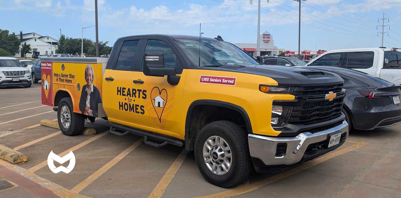 Hearts for Homes nonprofit truck in a distinctive yellow livery with the line Help a Senior Stay in Their Home