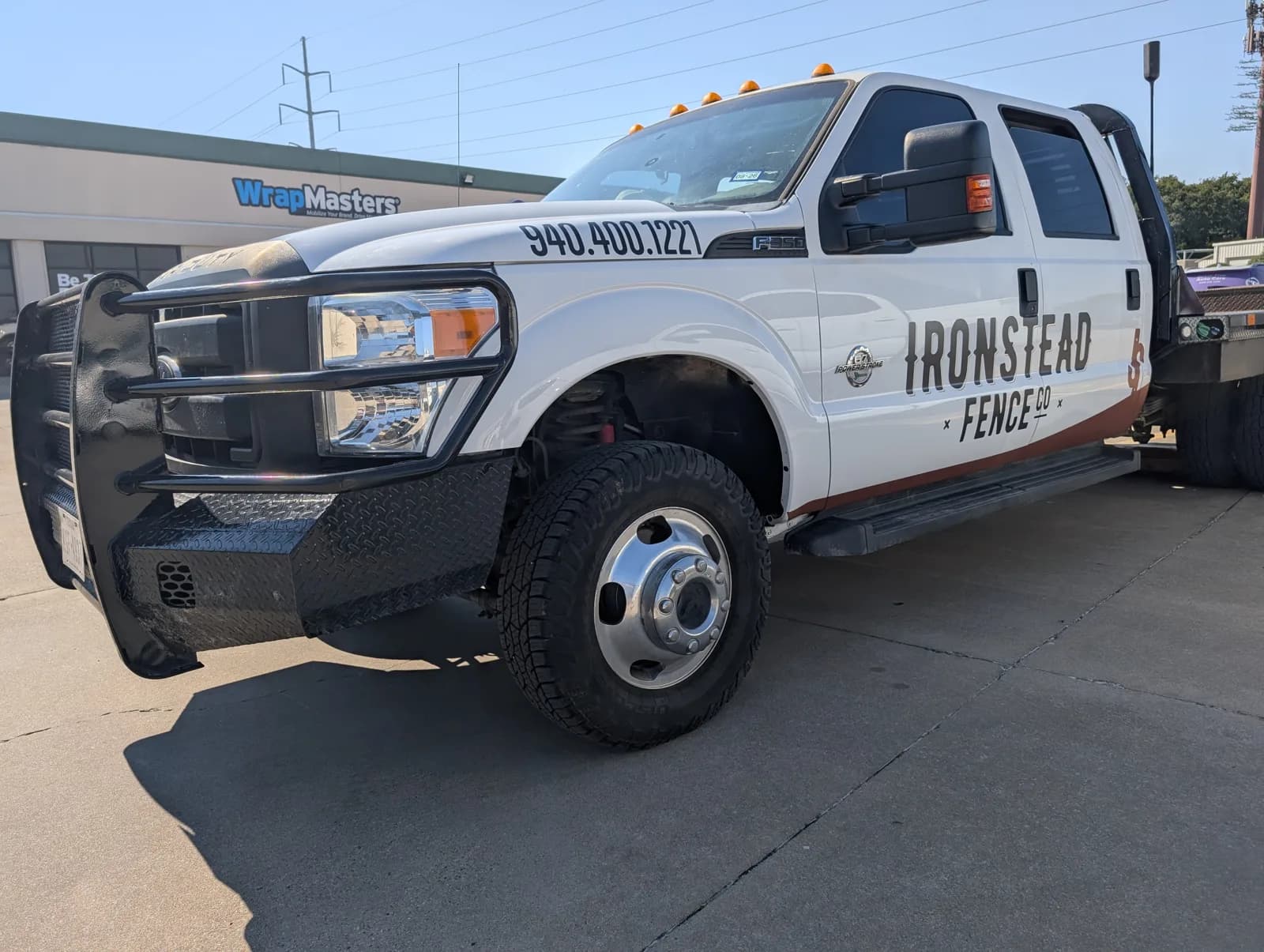 Ironstead Fence Co. flatbed front three-quarter view outside WrapMasters in Denton