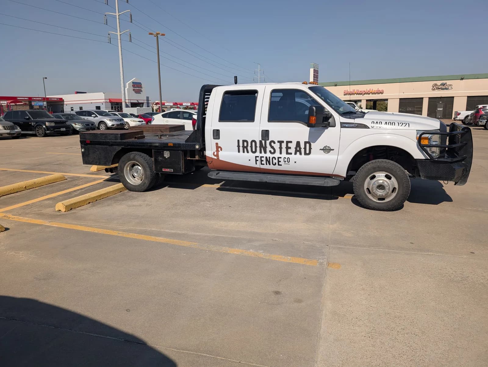 Ironstead Fence Co. Ford F-350 flatbed wrapped in white with the Ironstead name and a brown stripe, by WrapMasters