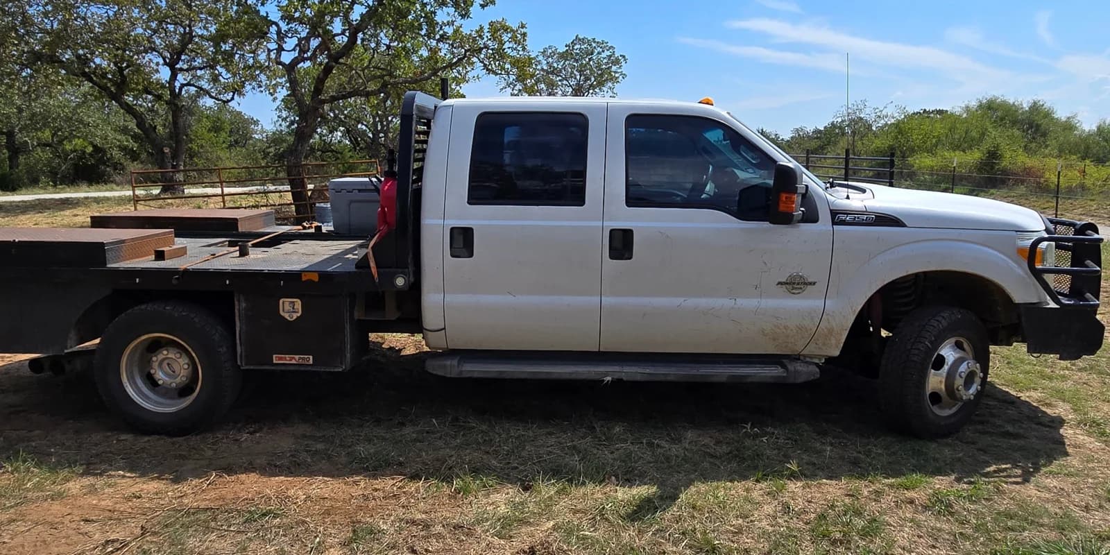 The company's Ford F-350 flatbed before the rebrand: plain white with no name on it, parked at a ranch job site
