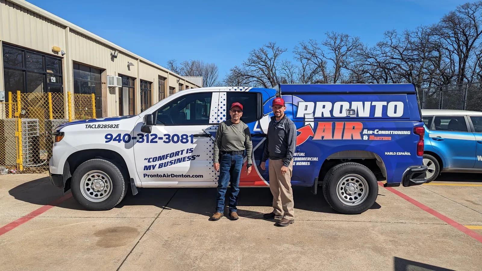 Pronto Air owners standing beside their wrapped HVAC pickup truck at the WrapMasters shop in Denton
