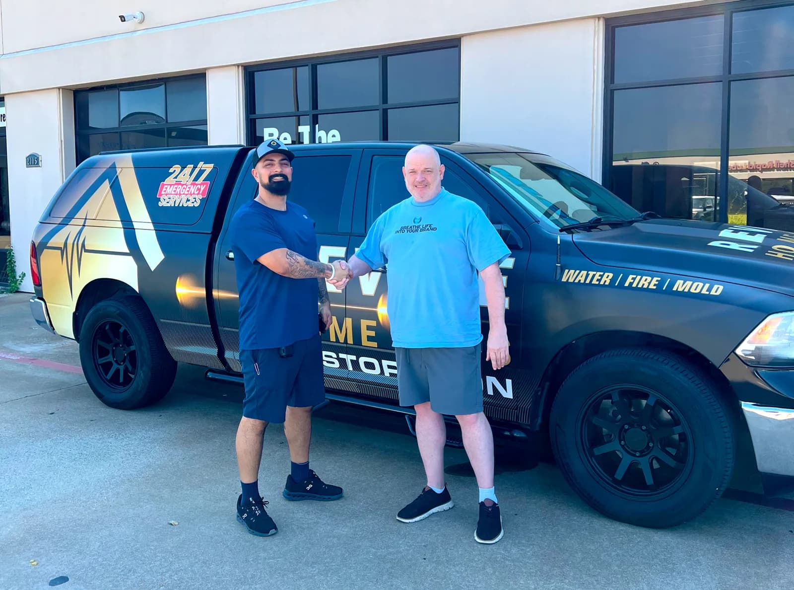 Revive Home Pros owner and WrapMasters shaking hands beside the wrapped pickup at delivery