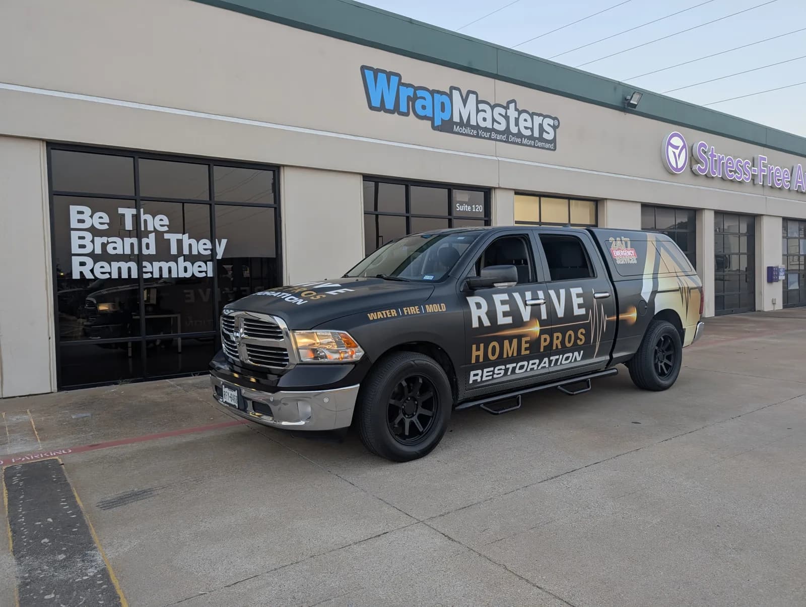 Revive Home Pros Restoration Ram pickup wrapped in black, white, and gold outside WrapMasters in Denton
