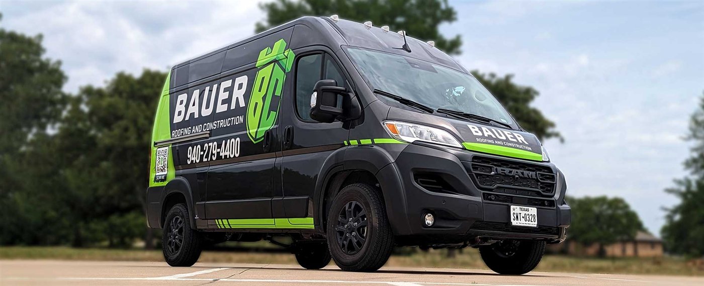 Bauer Roofing and Construction van with the company name in large white letters, the service category beneath it, and the phone number below that